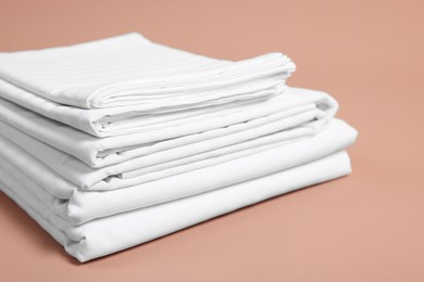 Stack of clean bed linens on beige background, closeup