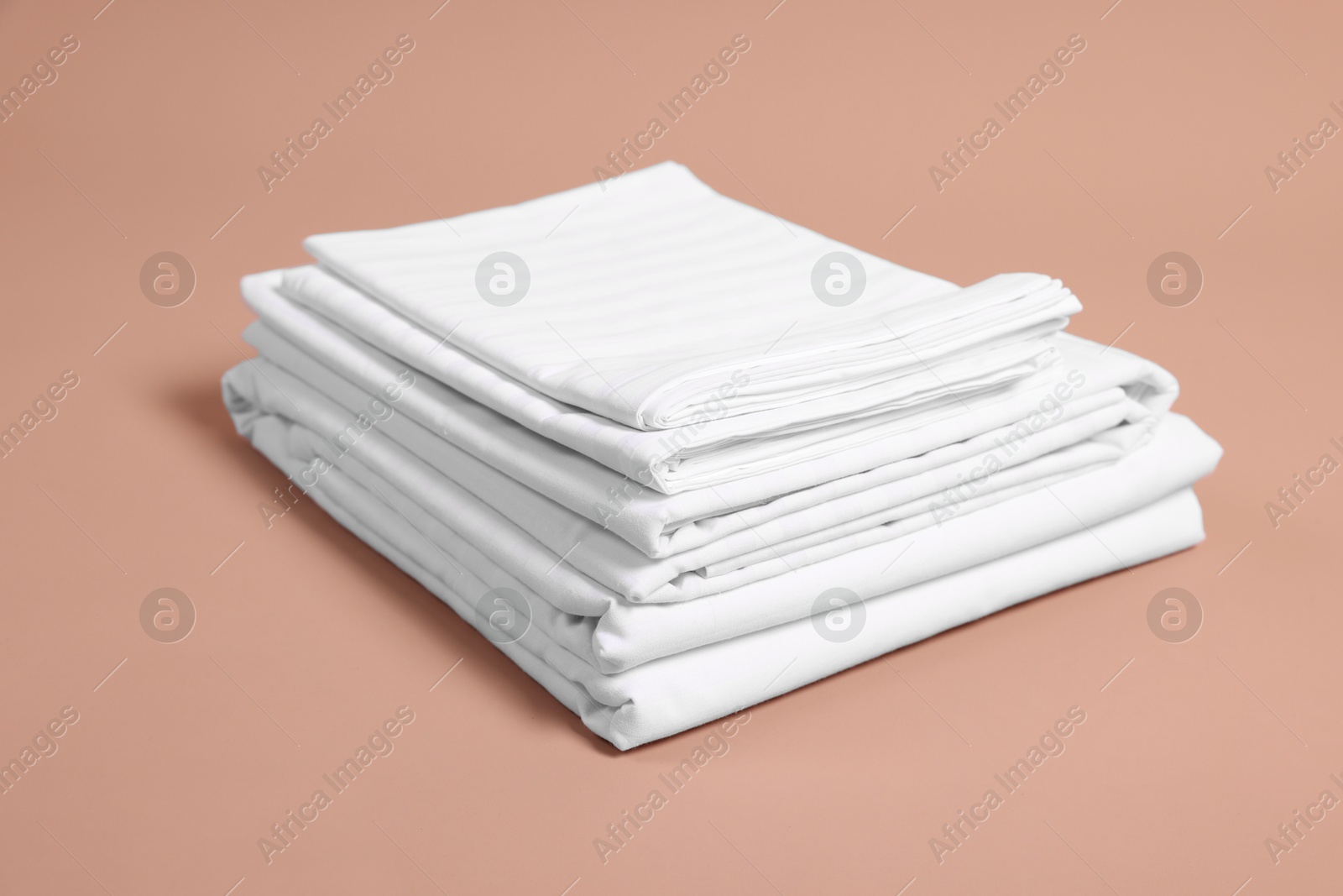 Photo of Stack of clean bed linens on beige background