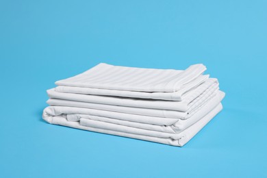 Photo of Stack of clean bed linens on light blue background