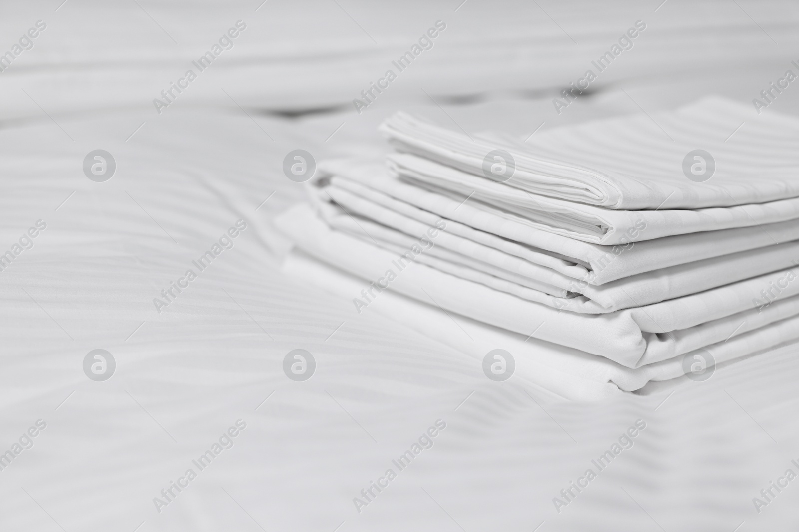 Photo of Stack of clean linens on bed indoors, closeup. Space for text