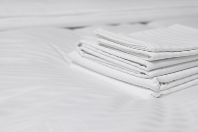 Photo of Stack of clean linens on bed indoors, closeup. Space for text