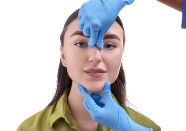 Doctor checking patient's nose before plastic surgery operation on white background, closeup