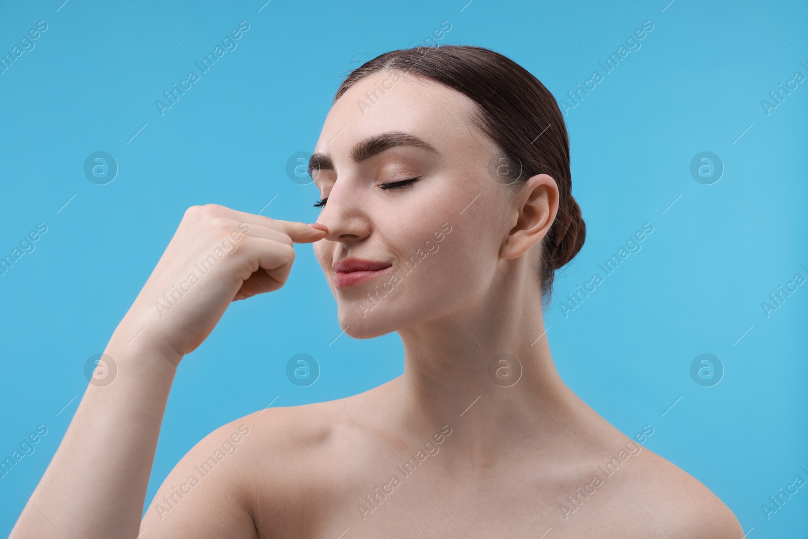 Photo of Woman touching her nose on light blue background