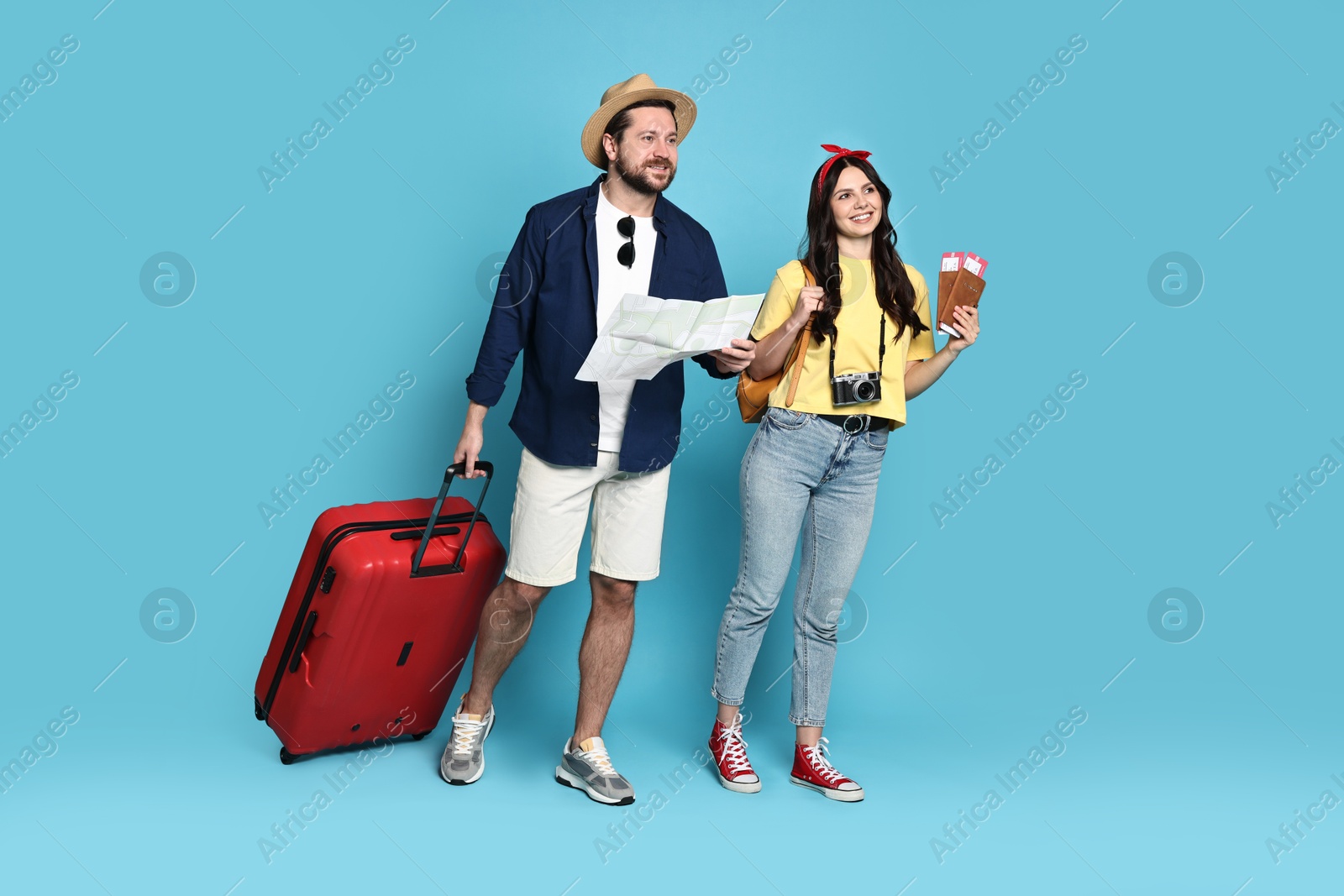 Photo of Tourism. Happy couple with map and suitcase on light blue background