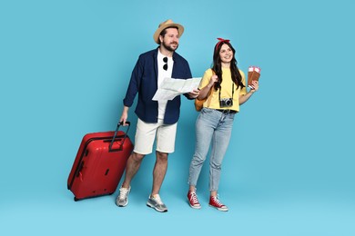 Photo of Tourism. Happy couple with map and suitcase on light blue background