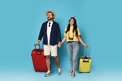 Tourism. Happy couple with suitcases on light blue background