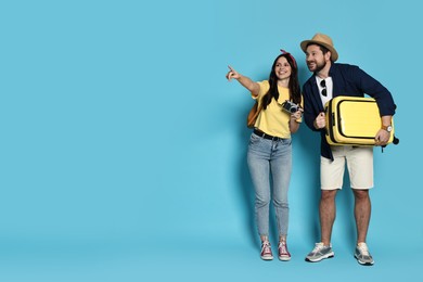 Photo of Tourism. Happy couple with suitcase on light blue background, space for text