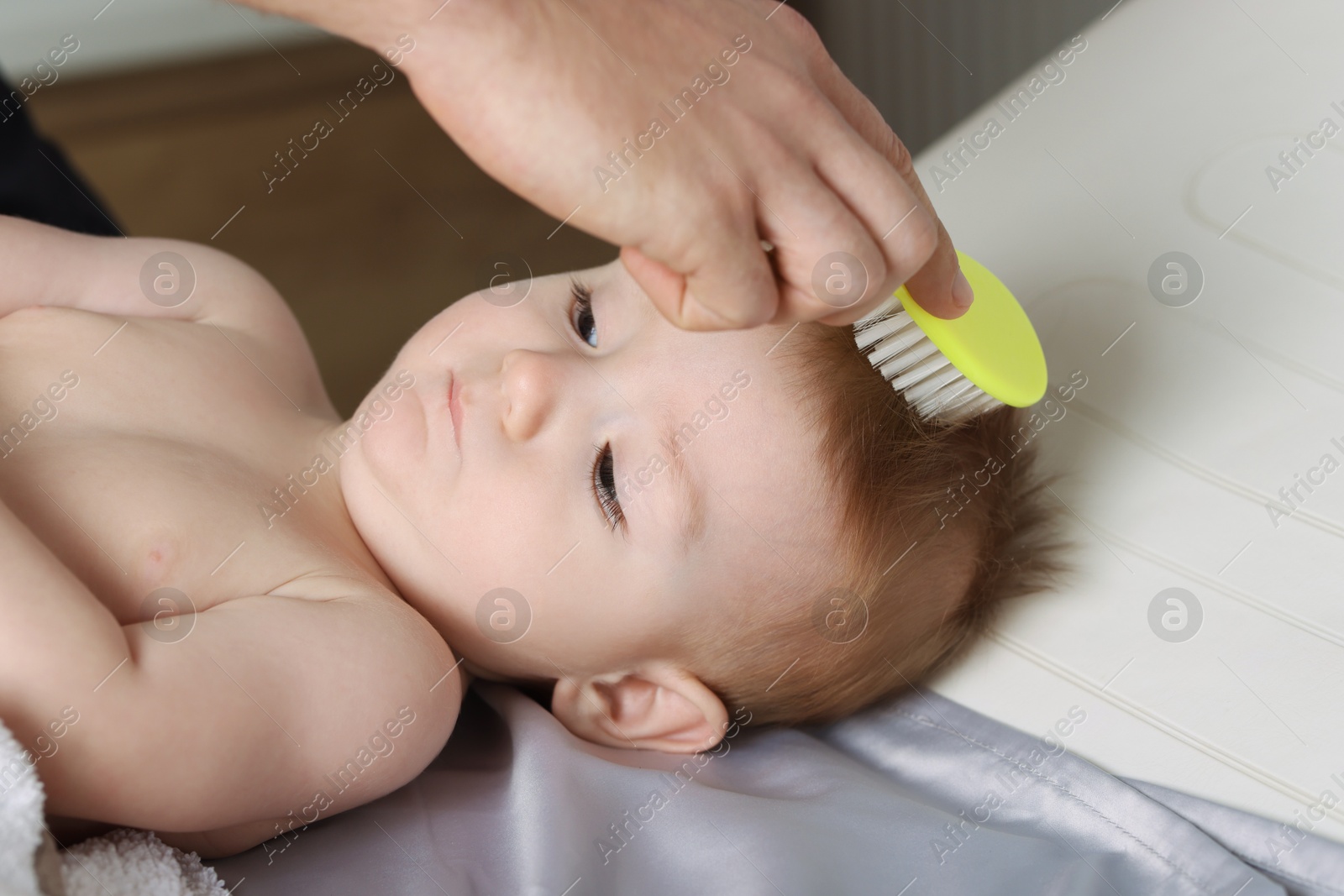 Photo of Man brushing hair of his little baby indoors, closeup