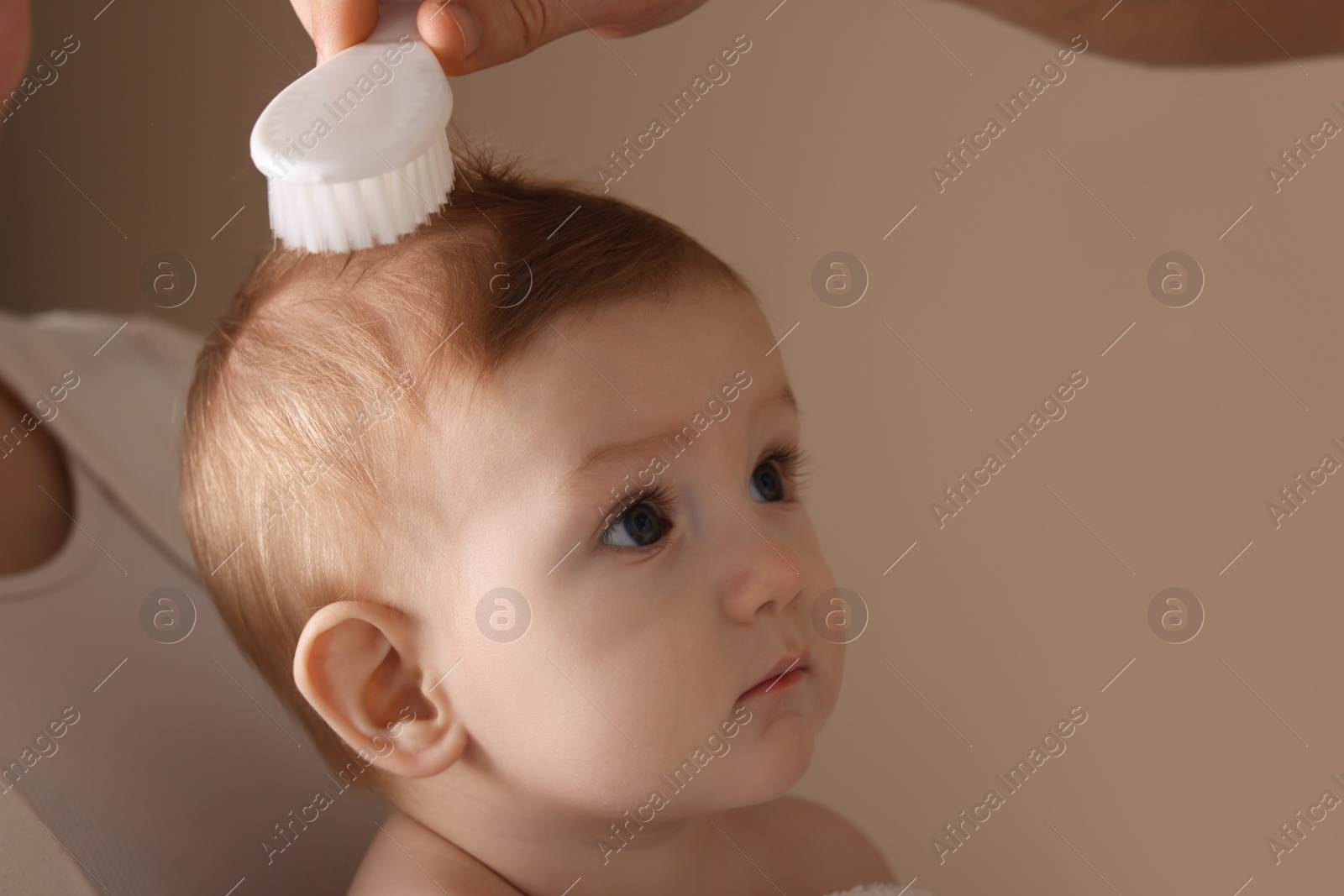 Photo of Parents brushing hair of their little baby on dark beige background, closeup. Space for text