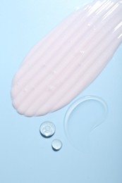 Photo of Cream and gel samples on light blue background, top view