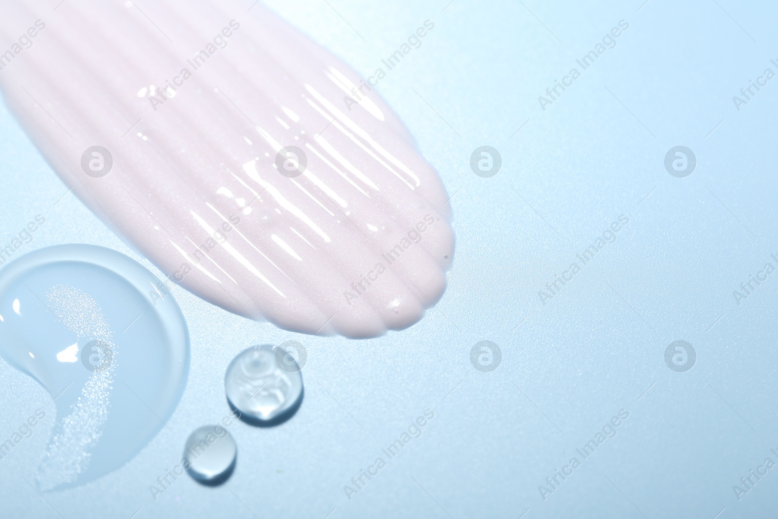 Photo of Cream and gel samples on light blue background, top view. Space for text