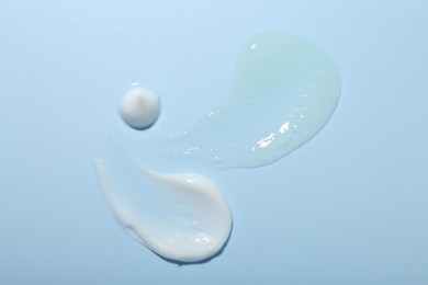 Photo of Cream and gel samples on light blue background, top view