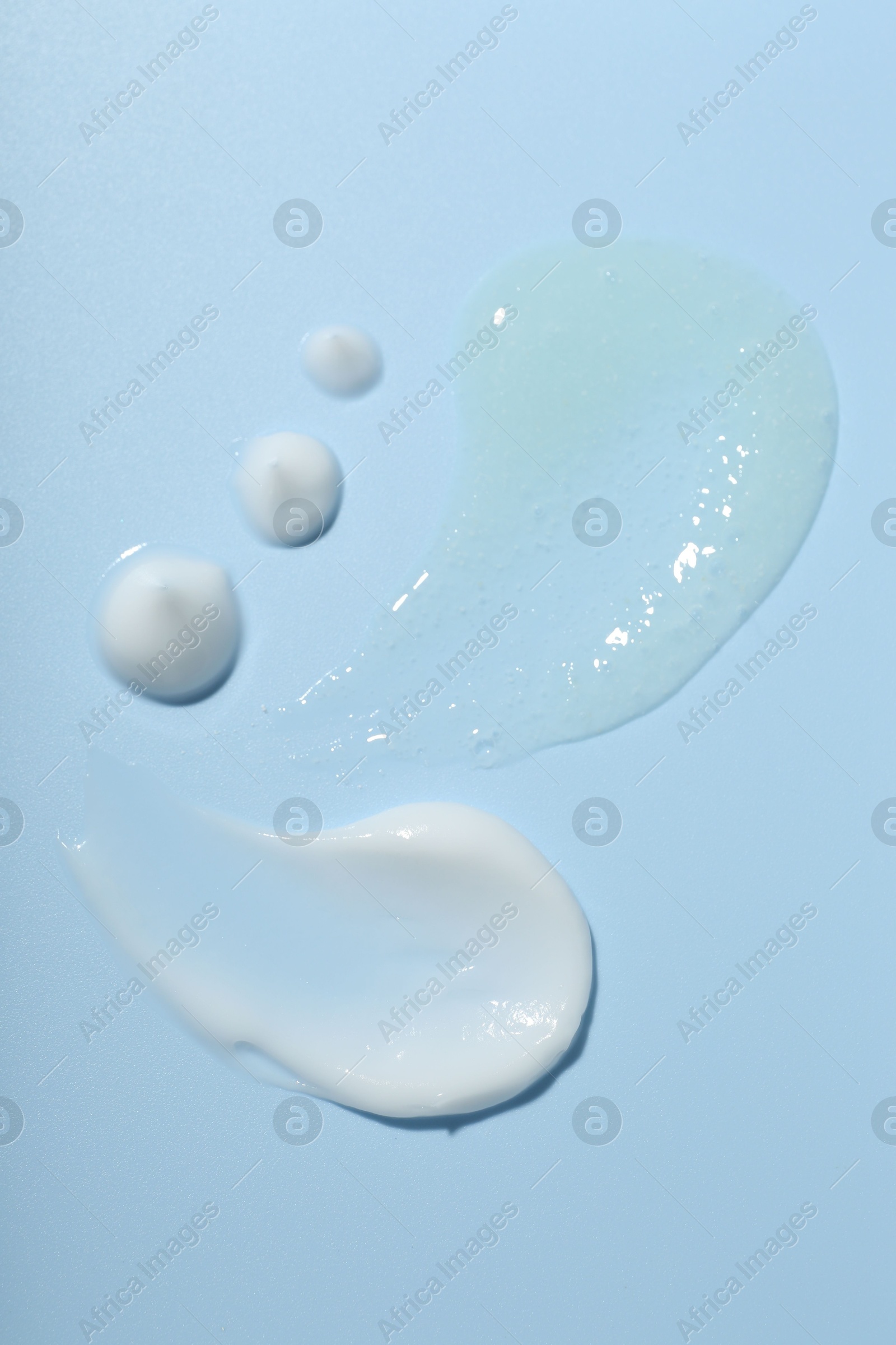 Photo of Cream and gel samples on light blue background, top view