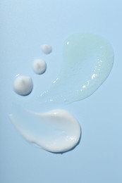 Photo of Cream and gel samples on light blue background, top view