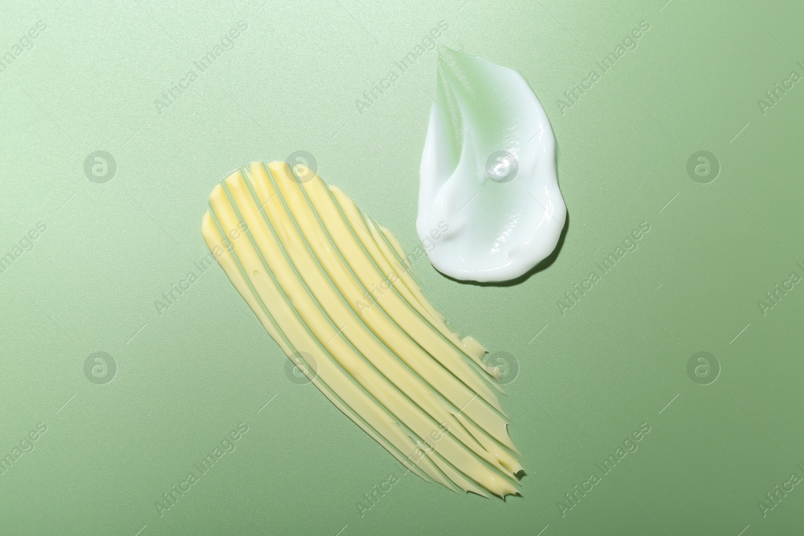 Photo of Cream samples on green background, top view