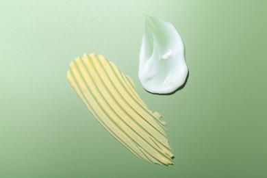 Cream samples on green background, top view