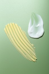 Photo of Cream samples on green background, top view