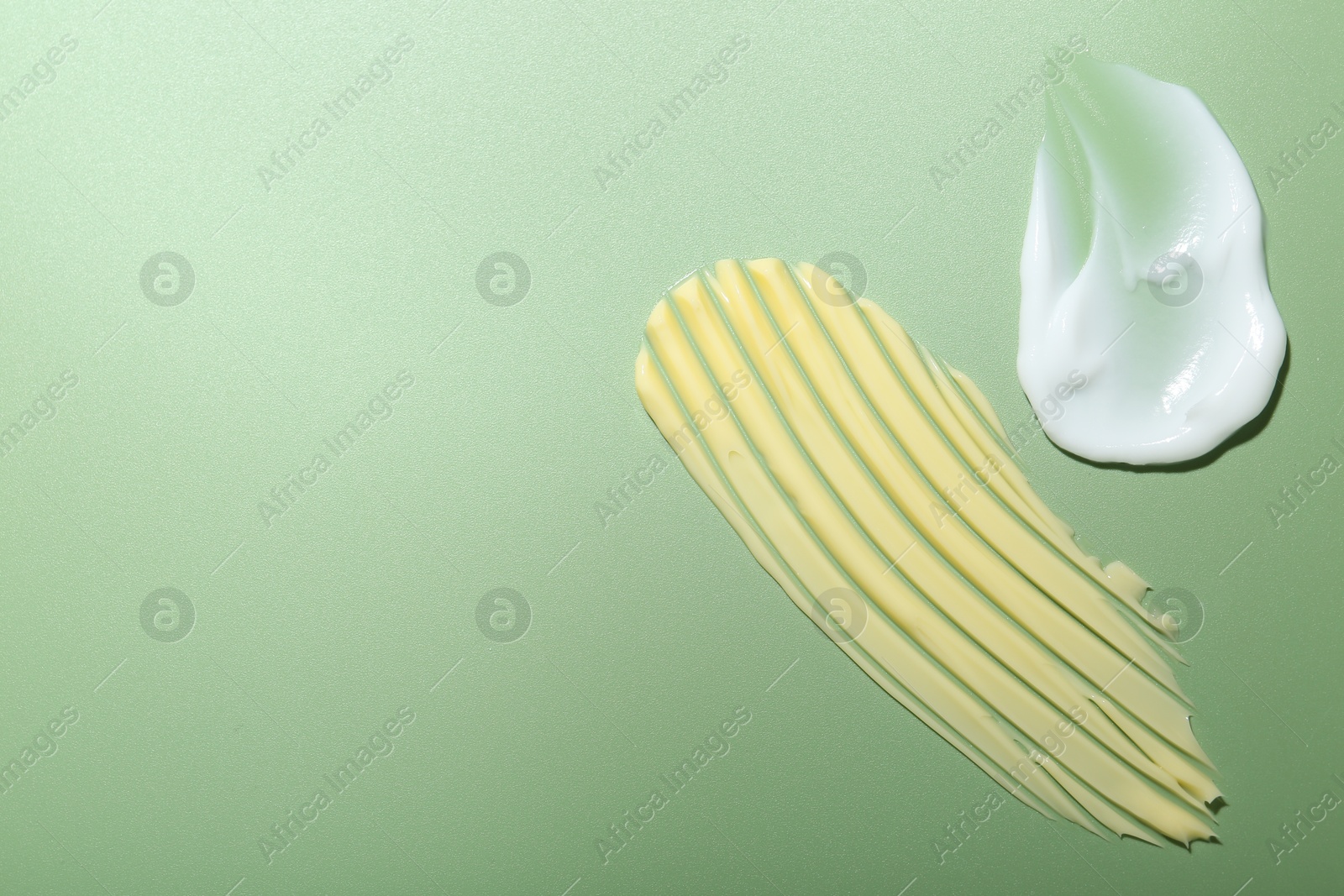 Photo of Cream samples on green background, top view. Space for text