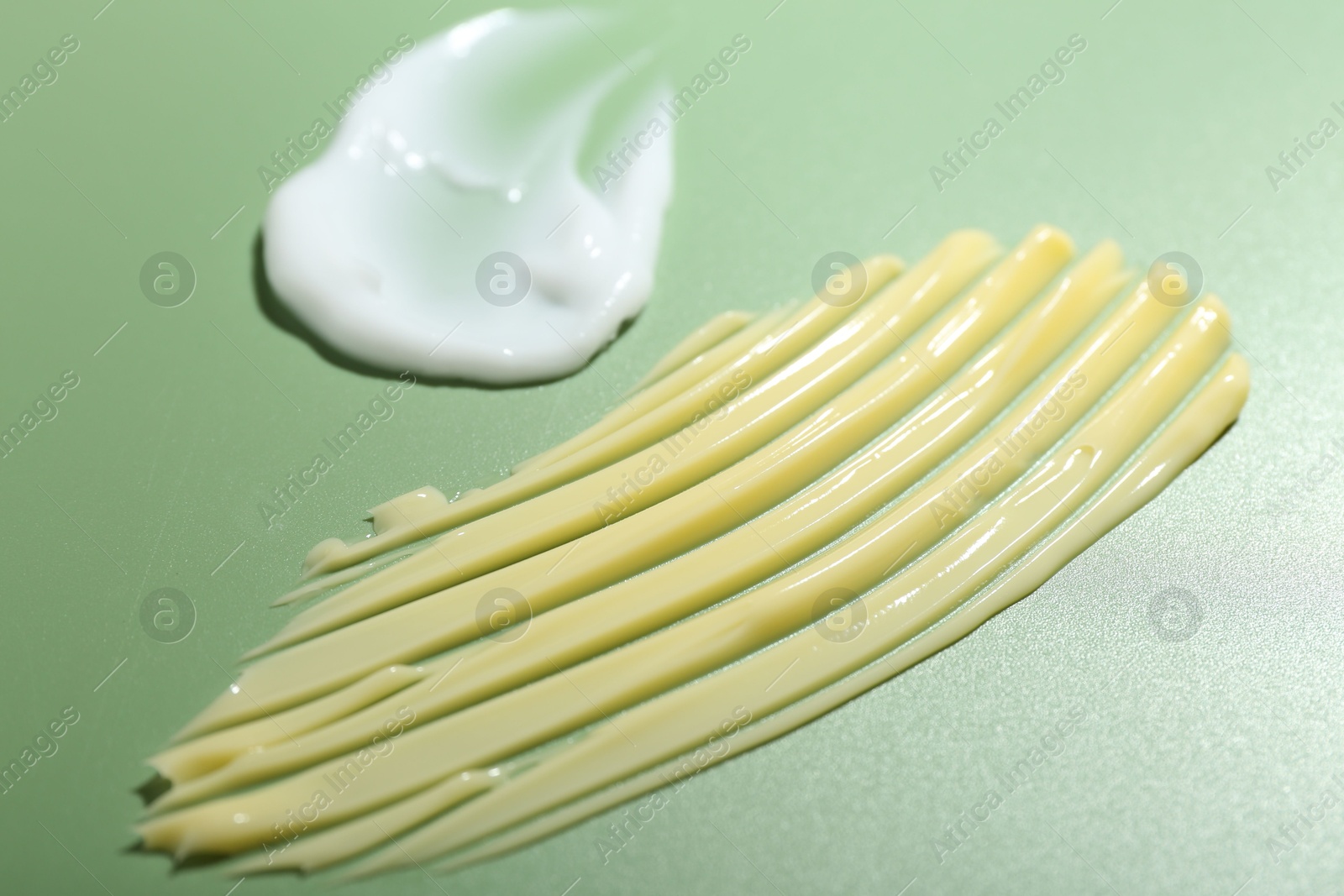 Photo of Cream samples on green background, closeup. Skincare product