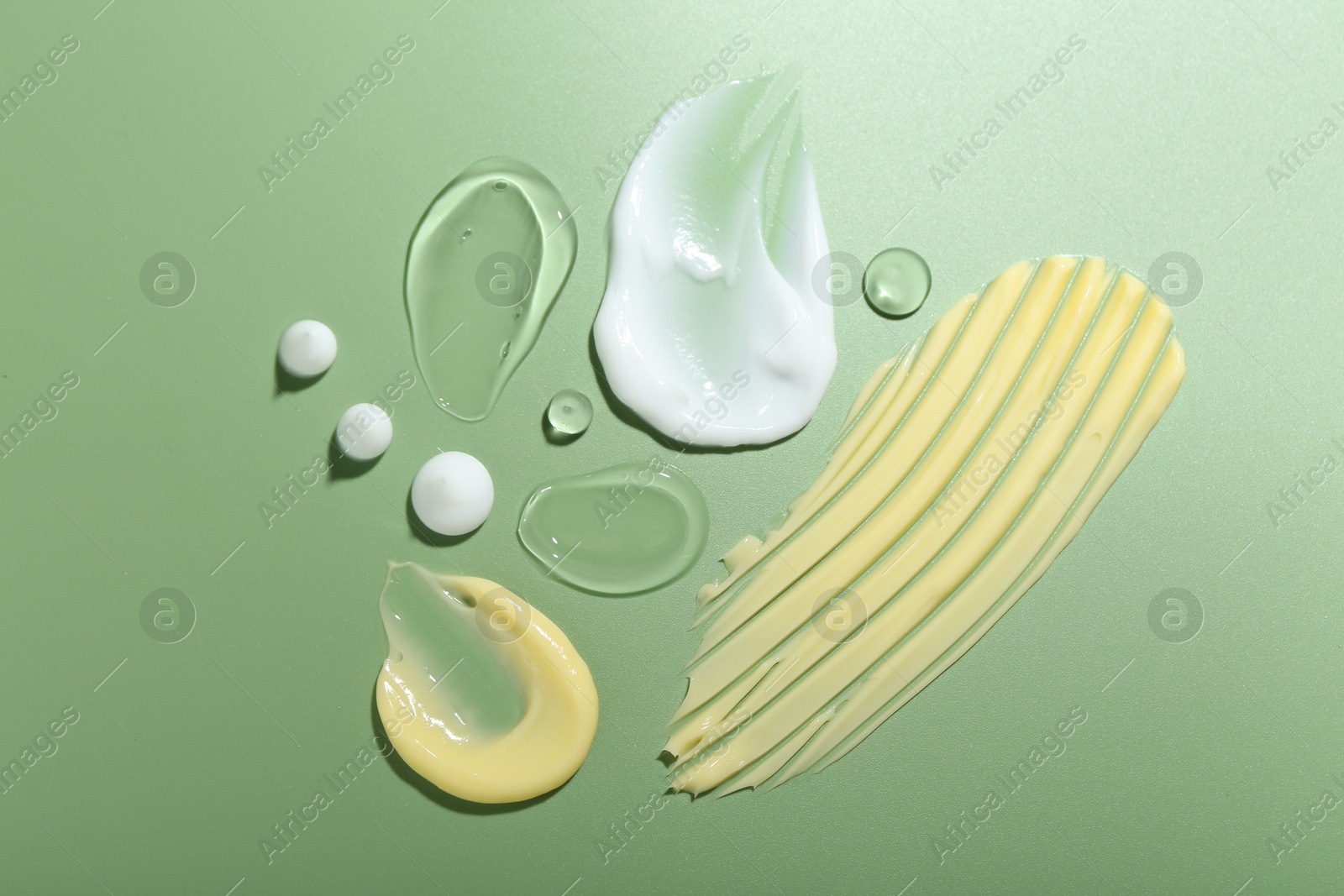 Photo of Cream and gel samples on green background, top view