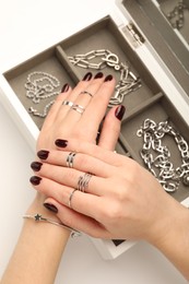 Woman wearing beautiful rings and jewelry box with different accessories on white background, closeup