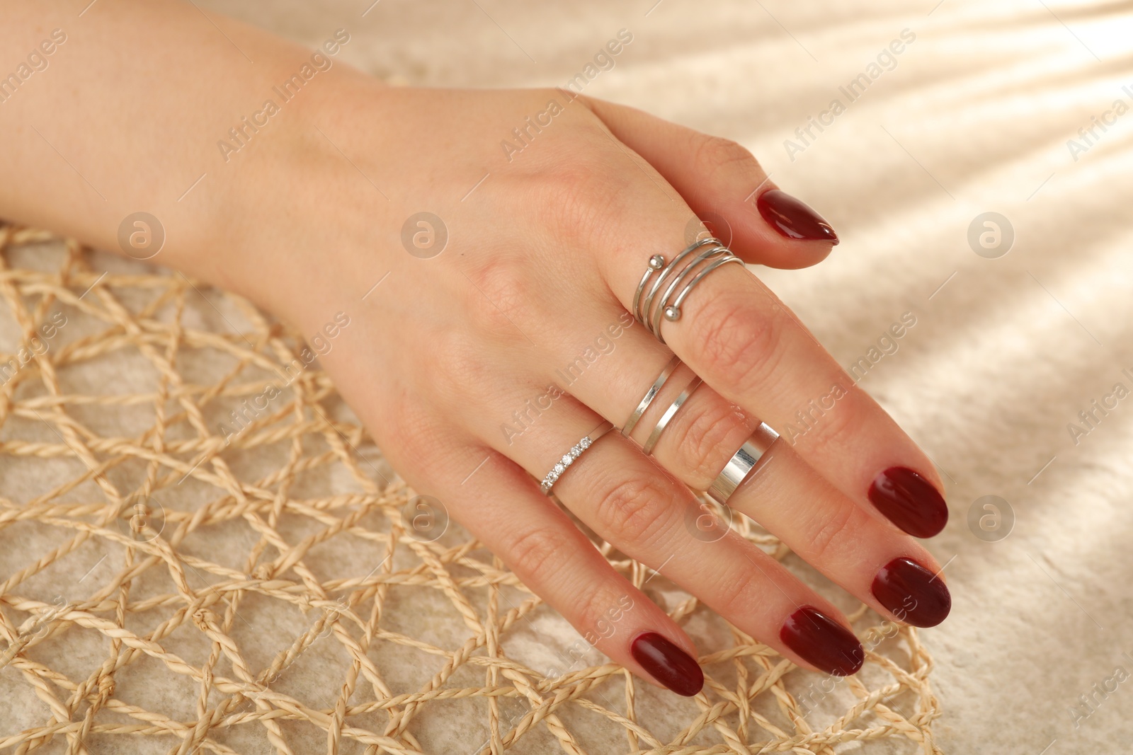 Photo of Woman wearing beautiful rings on beige background, closeup