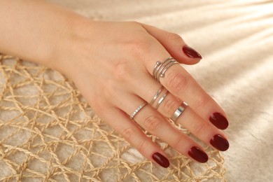 Woman wearing beautiful rings on beige background, closeup