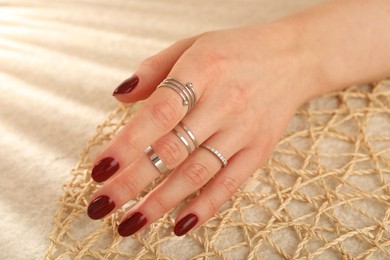 Woman wearing beautiful rings on beige background, closeup