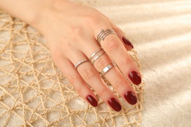 Photo of Woman wearing beautiful rings on beige background, closeup