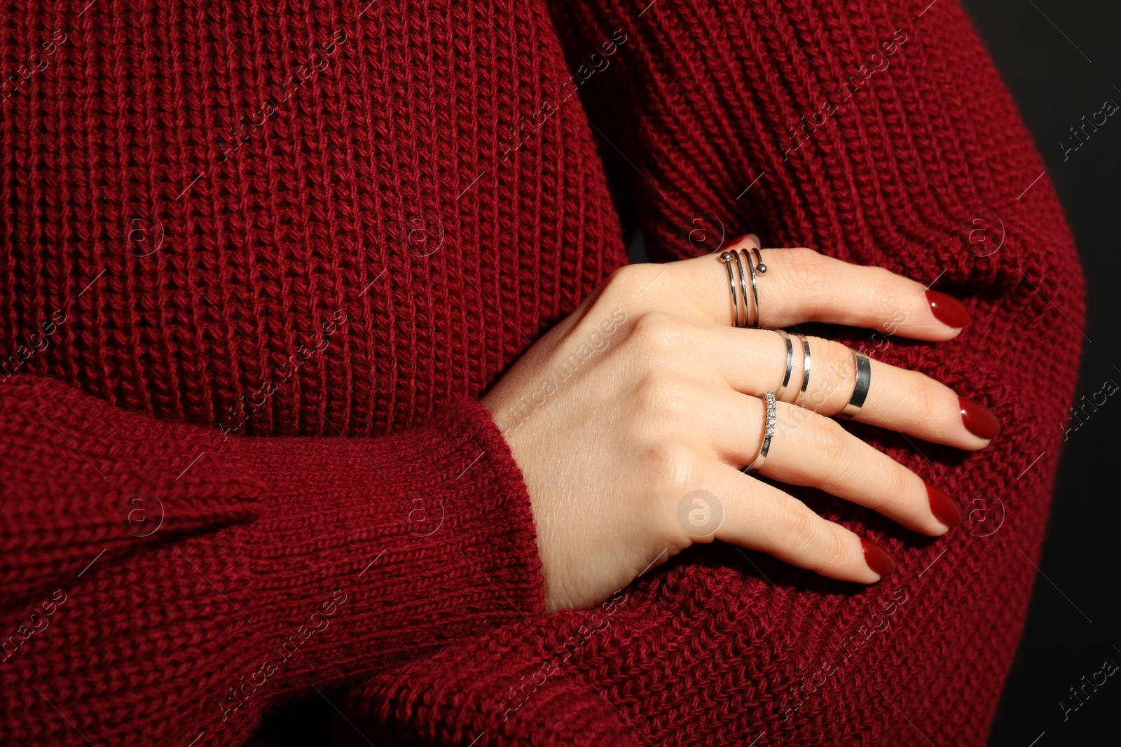 Photo of Woman wearing beautiful rings on dark background, closeup