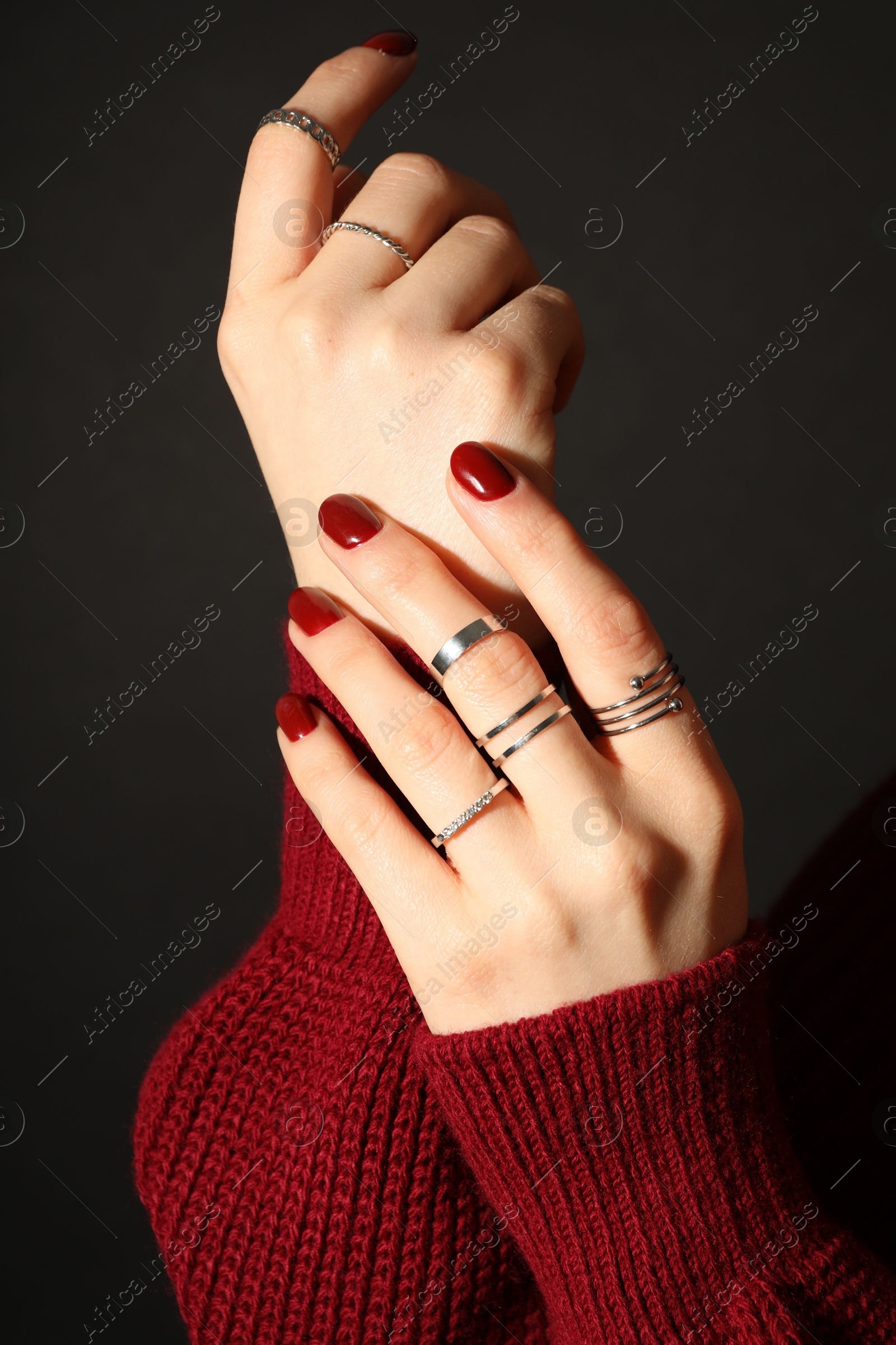 Photo of Woman wearing beautiful rings on dark background, closeup