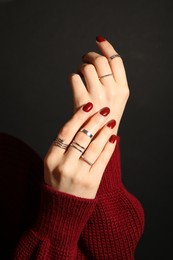 Photo of Woman wearing beautiful rings on dark background, closeup