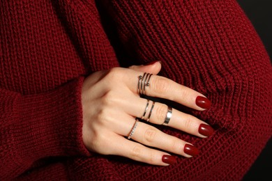 Photo of Woman wearing beautiful rings on dark background, closeup