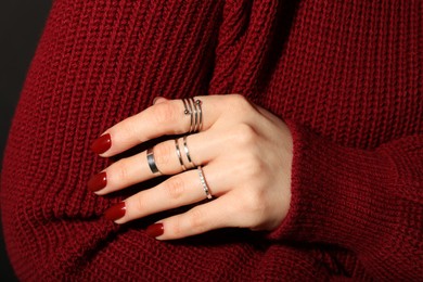 Photo of Woman wearing beautiful rings on dark background, closeup