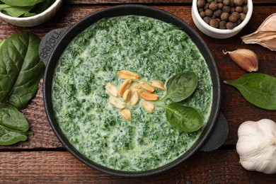 Delicious spinach sauce with peanuts served on wooden table, flat lay