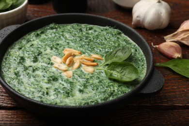 Photo of Delicious spinach sauce with peanuts served on wooden table, closeup