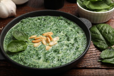 Delicious spinach sauce with peanuts served on wooden table, closeup