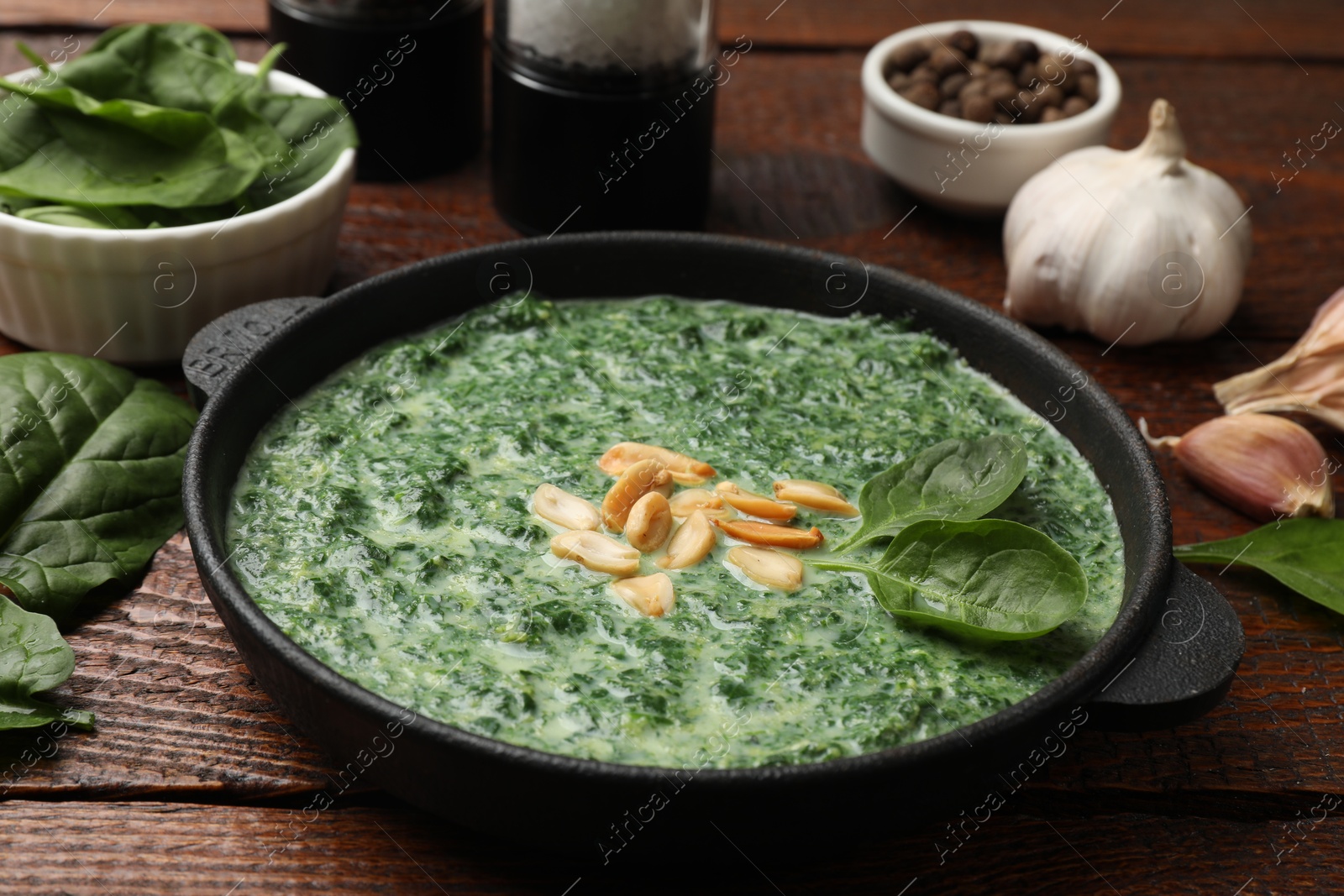 Photo of Delicious spinach sauce with peanuts served on wooden table, closeup