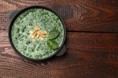 Photo of Delicious spinach sauce with peanuts on wooden table, top view. Space for text