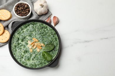 Photo of Delicious spinach sauce with peanuts and crackers on white table, flat lay. Space for text