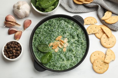 Photo of Delicious spinach sauce with peanuts and crackers on white table, flat lay