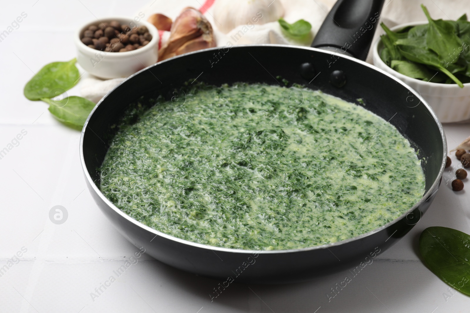 Photo of Delicious spinach sauce served on white tiled table, closeup