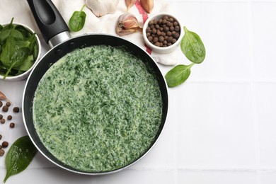 Delicious spinach sauce served on white tiled table, flat lay. Space for text