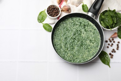 Delicious spinach sauce served on white tiled table, flat lay. Space for text