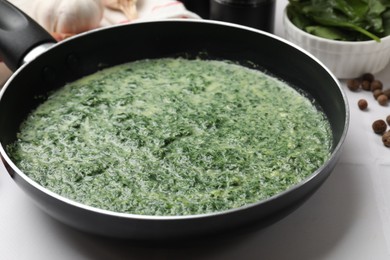 Photo of Delicious spinach sauce served on white tiled table, closeup