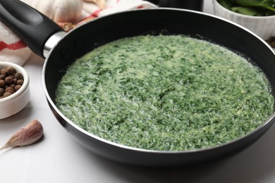 Delicious spinach sauce served on white tiled table, closeup