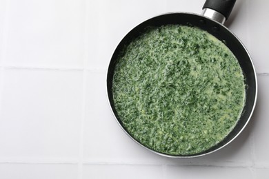 Photo of Delicious spinach sauce on white tiled table, top view. Space for text