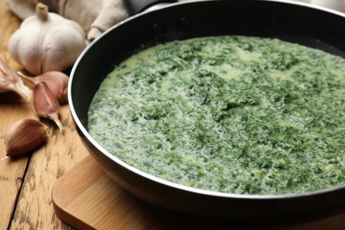 Delicious spinach sauce served on wooden table, closeup