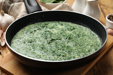 Delicious spinach sauce served on wooden table, closeup