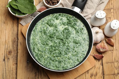 Photo of Delicious spinach sauce served on wooden table, flat lay